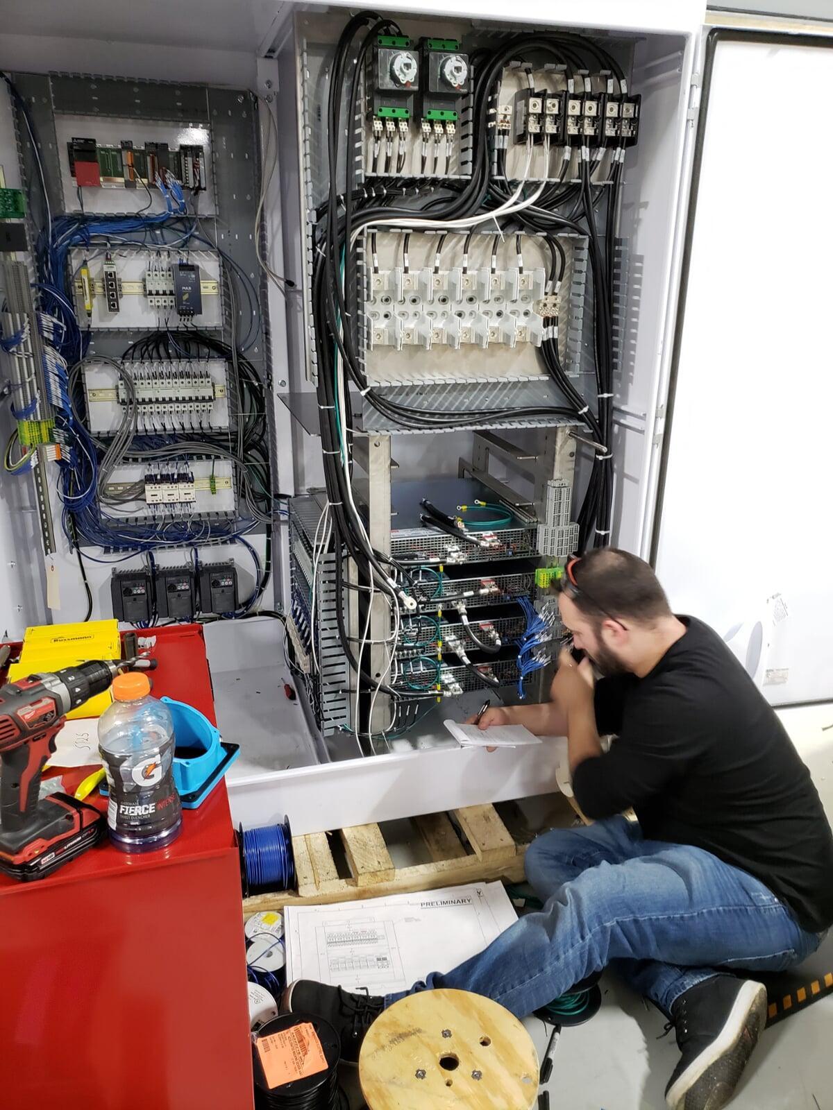 A technician wiring a high-power electrical system for coil control