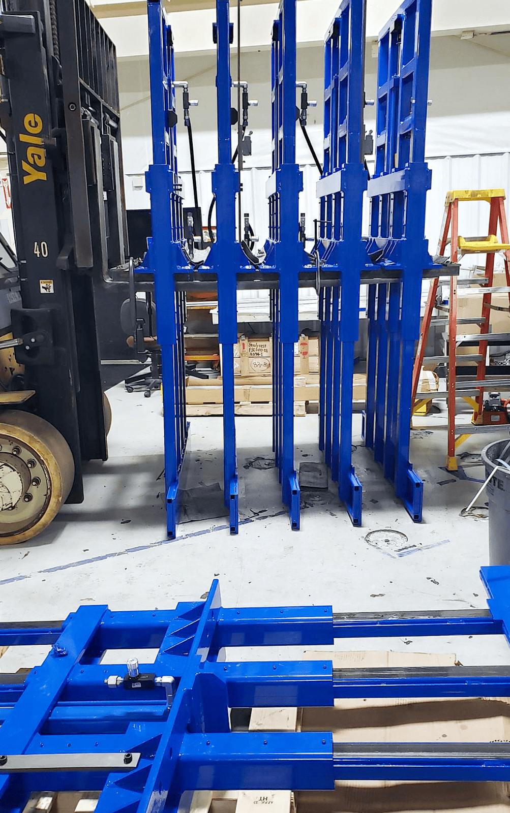 Large fabricated and machined assemblies are loaded on a fork truck after receiving blue powder coating